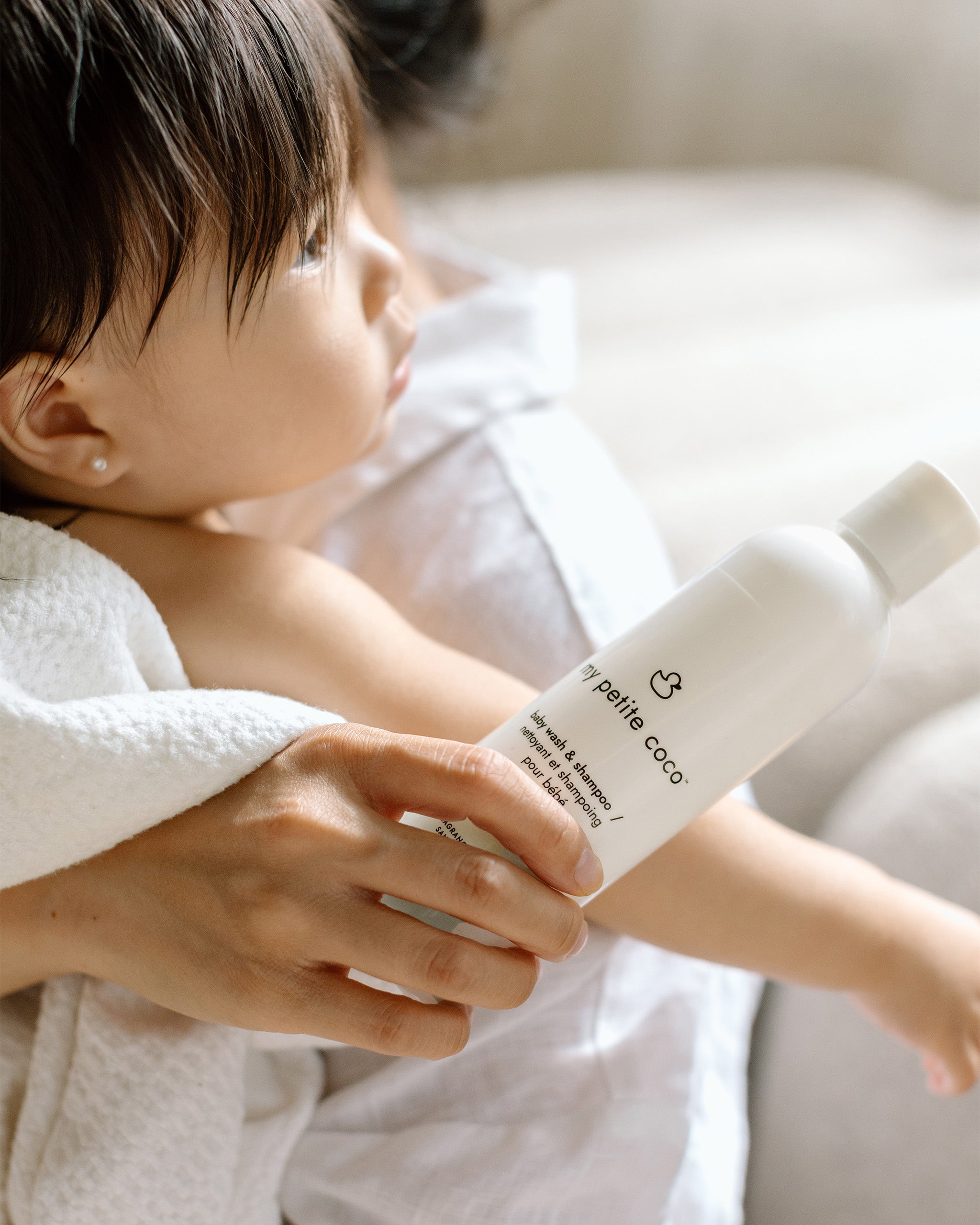 A bottle of My Petite Coco baby wash & shampoo in a parent’s hands.